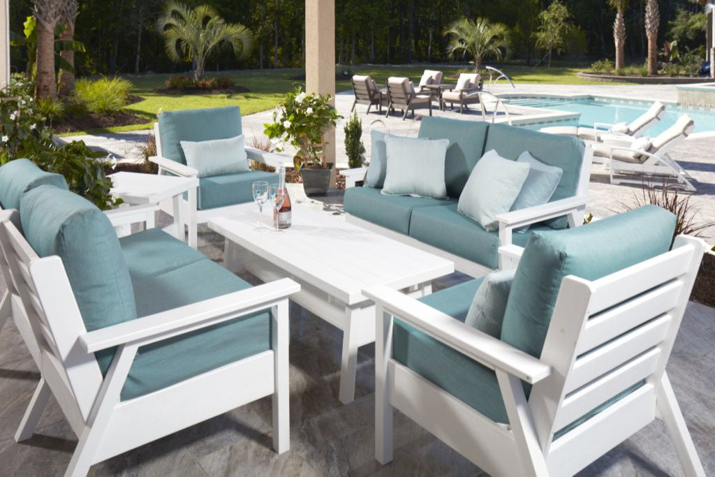 Outdoor patio furniture set with blue cushions by a poolside.